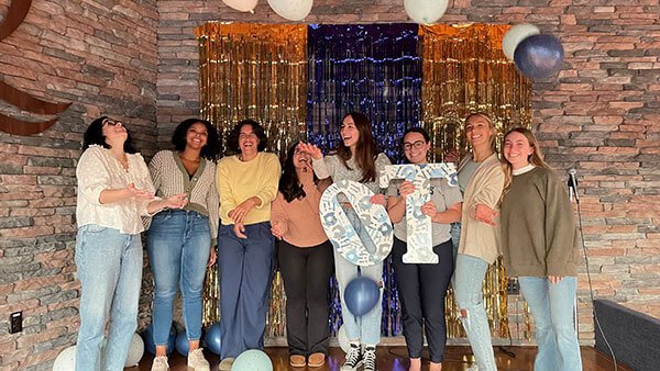 Students taking a picture together and throwing balloons at an OT Student Advisory Board party