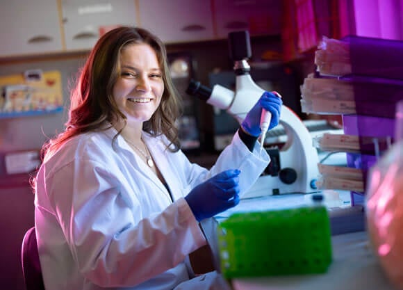 Photo of a student in a lab with a microscope.