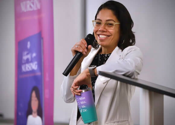 Dr. Tina Loarte-Rodriguez holding a microphone while smiling