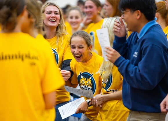 Individuals standing and laughing during Orientation