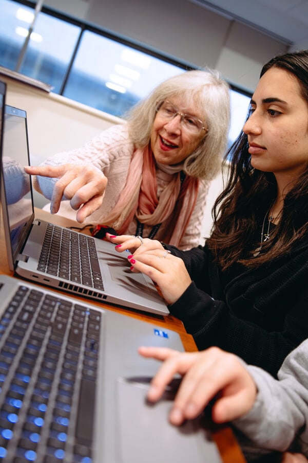 Professor assisting a student by pointing to something on a computer screen