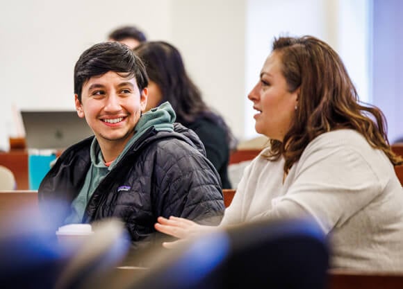 A male student smiles at a female student talking