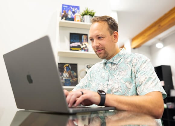 A male grad student looking at a laptop in a modern office