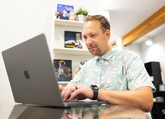 A Quinnipiac graduate student works on a laptop in a brightly lit room