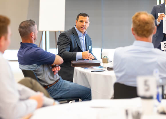A professional from a company speaks with colleagues at a round table